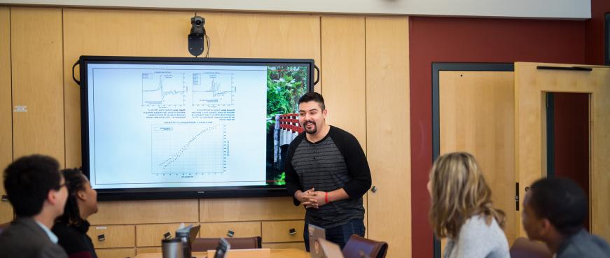 A student gives a presentation on a screen in a classroom.